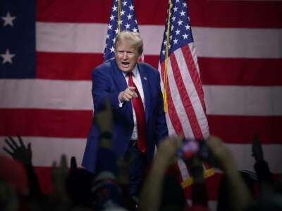 Donald Trump shouts at a crowd gathered at a rally and points