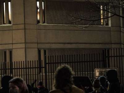 Demonstrators make noise outside of a jail as a person inside places their hand on a window during an anti-police protest on January 24, 2021, in Tacoma, Washington.