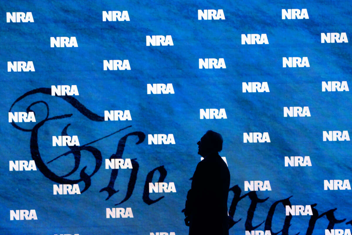 The silhouette of NRA President Charles Cotton appears against a curtain with the NRA logo pattern.