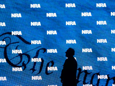 The silhouette of NRA President Charles Cotton appears against a curtain with the NRA logo pattern.