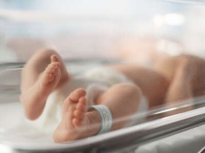 Newborn Baby Lying in Bassinet in a Maternity Hospital. Portrait of a Tiny Playful and Energetic Child with a Name ID Tag on the Leg. Healthcare, Pregnancy and Motherhood Concept