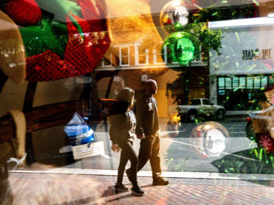 Reflected in a festively decorated shop window, shoppers peruse along State Street in downtown Redlands, California, on November 24, 2023.
