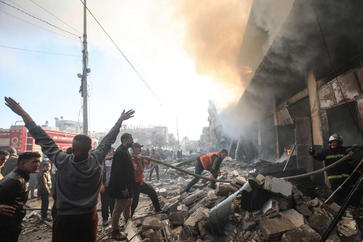 People watch as firefighters battle flames in a building hit by an Israeli strike in Khan Yunis in the southern Gaza Strip, on December 9, 2023.