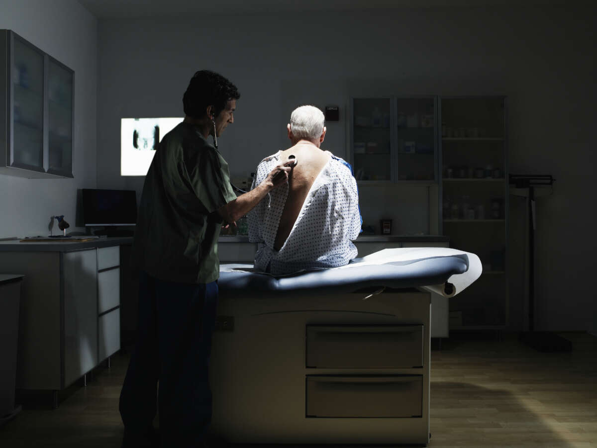 Doctor examines patient with stethoscope in medical exam room