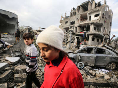 Palestinians search through building rubble for survivors following Israeli strikes on the al-Maghazi refugee camp in the central Gaza Strip on December 25, 2023.