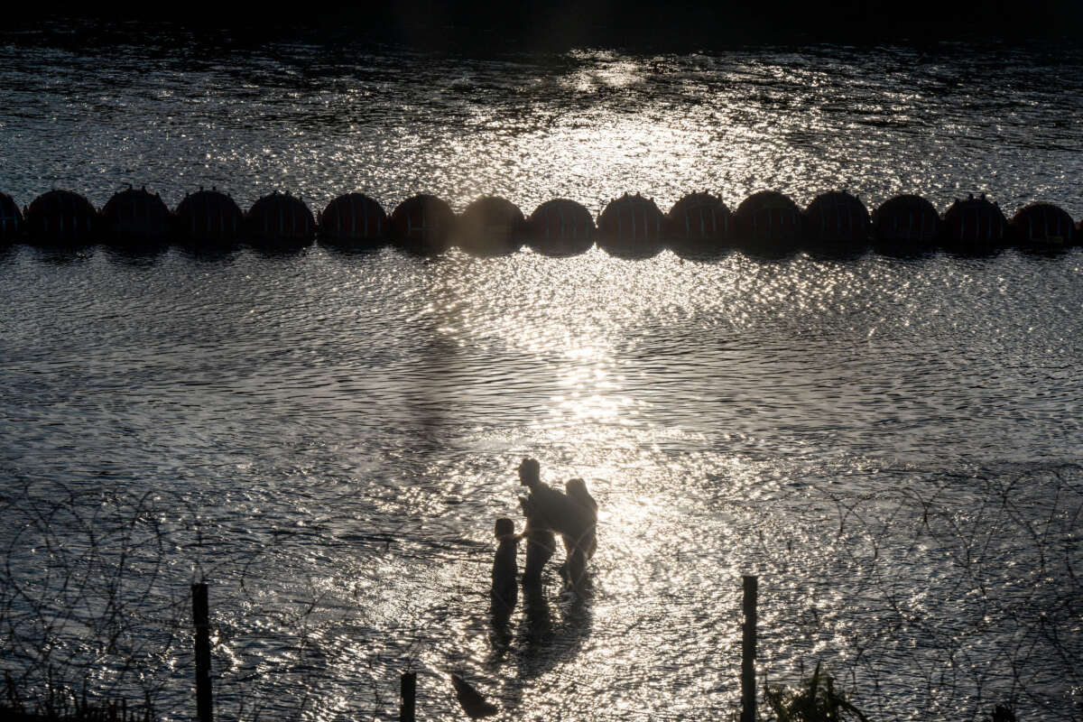 Migrants cross the Rio Grande river near the buoy barriers on September 11, 2023, in Eagle Pass, Texas.