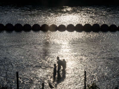 Migrants cross the Rio Grande river near the buoy barriers on September 11, 2023, in Eagle Pass, Texas.