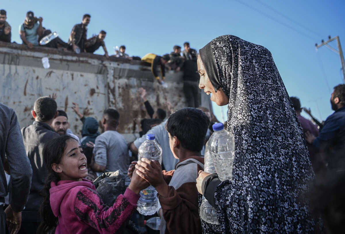 Palestinians flock to a truck carrying drinkable water, as they face the threat of hunger and thirst in Rafah, Gaza, on December 11, 2023.