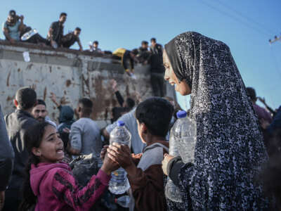 Palestinians flock to a truck carrying drinkable water, as they face the threat of hunger and thirst in Rafah, Gaza, on December 11, 2023.