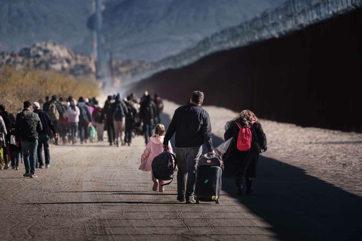 People walk beside the us/mexico border wall
