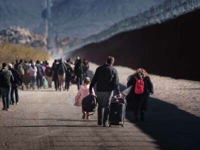 People walk beside the us/mexico border wall