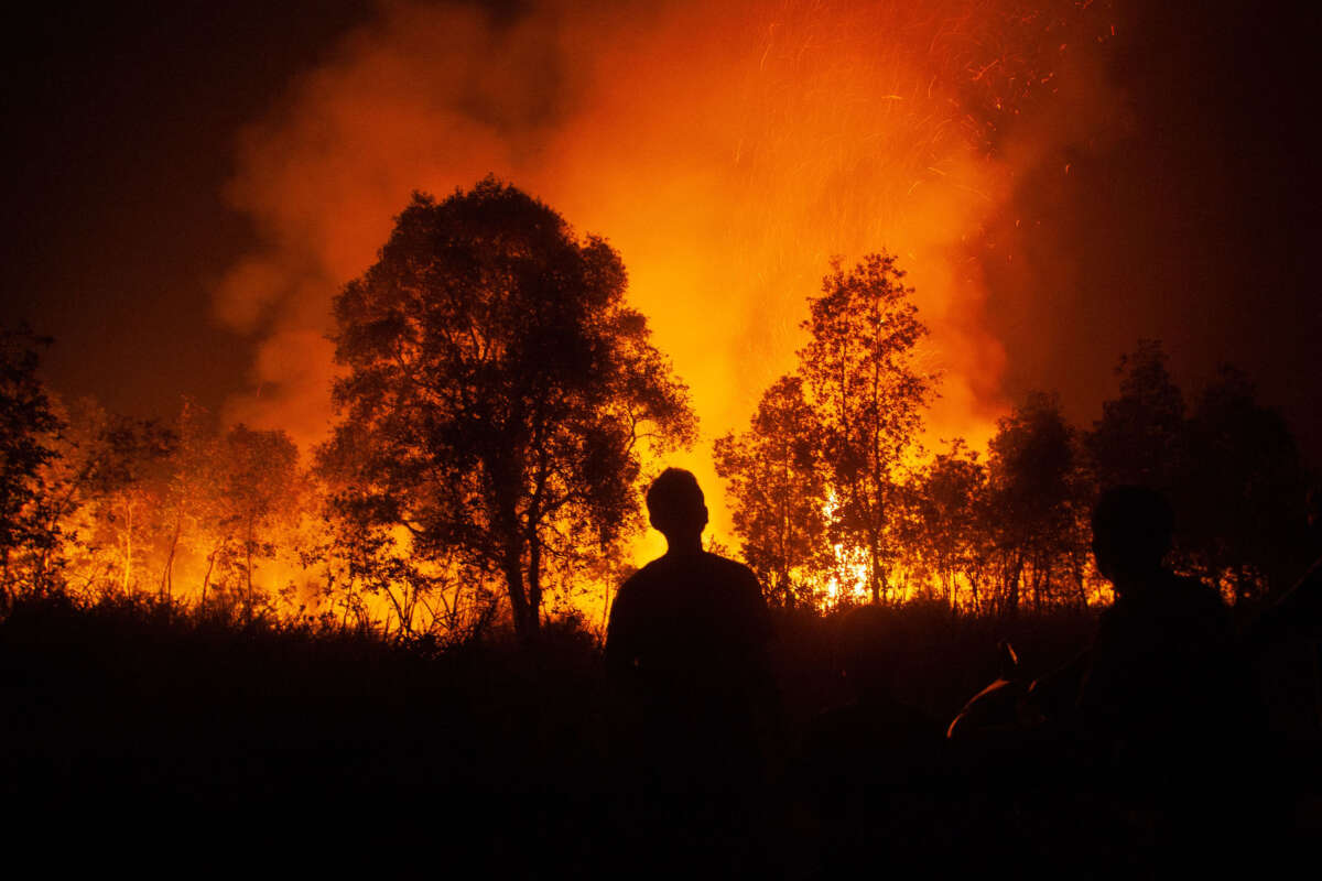 In this photo taken on October 10, 2023, a man looks at a forest fire as it approaches houses in Ogan Ilir, South Sumatra.