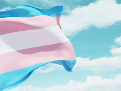 Transgender flag flying over blue cloudy sky