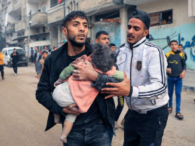 A man carries a child injured during Israeli bombardment in Rafah, in the southern Gaza Strip, on December 14, 2023.