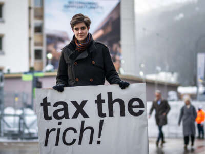 BNSF heiress Marlene Engelhorn holds a sign reading "TAX THE RICH" during an outdoor demonstration