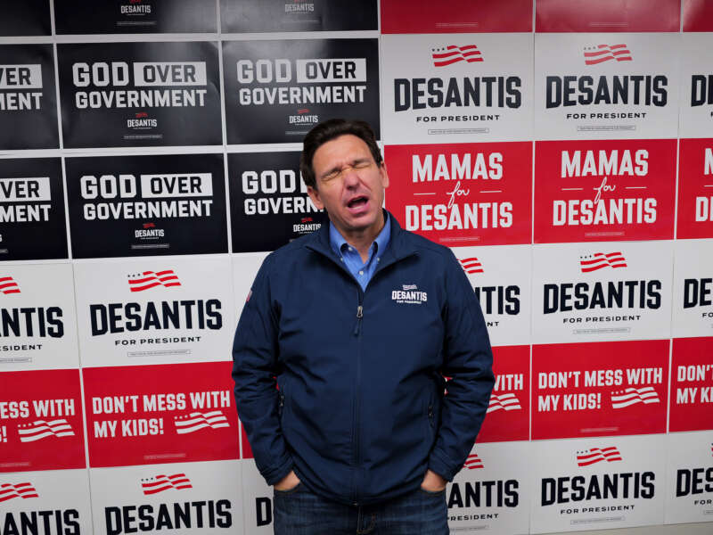 Ron Desantis makes a face in front of his campaign signage, that has been arranged into the form of a facsimile of the U.S. flag