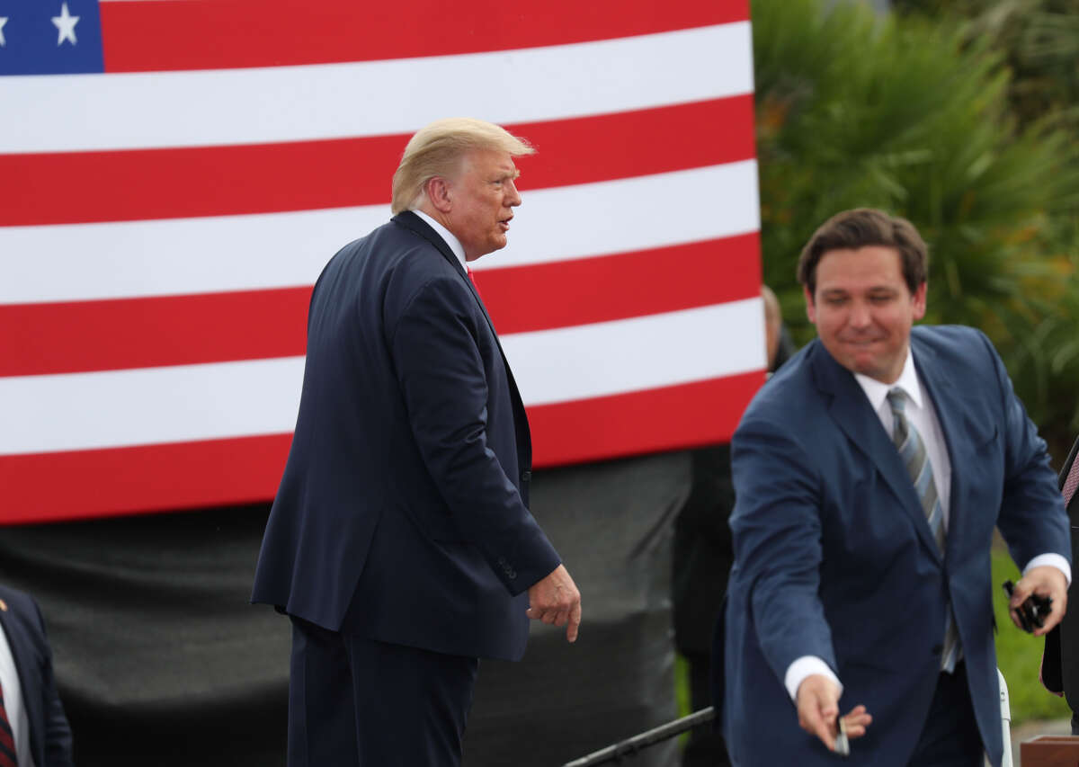 Then-President Donald Trump exits from the stage after speaking about the environment during a stop at the Jupiter Inlet Lighthouse as Florida Gov. Ron DeSantis hands out pens to people in the crowd on September 8, 2020, in Jupiter, Florida.