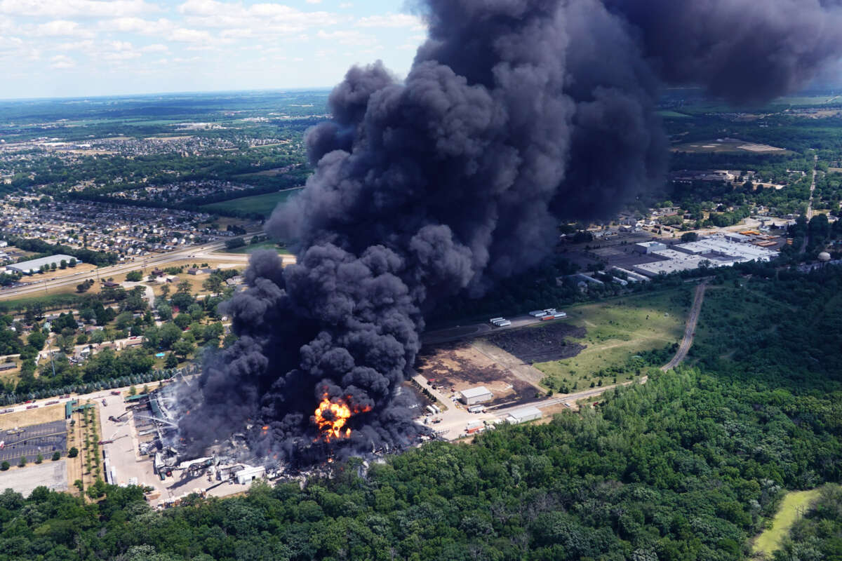 An aerial view of an explosion at a chemical plant that spews black smoke into the air mere blocks from a residential neighborhood