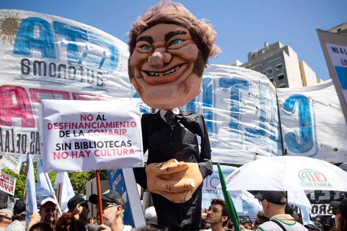 Protesters march with a large paper mache puppet of Argentine president Javier Milei