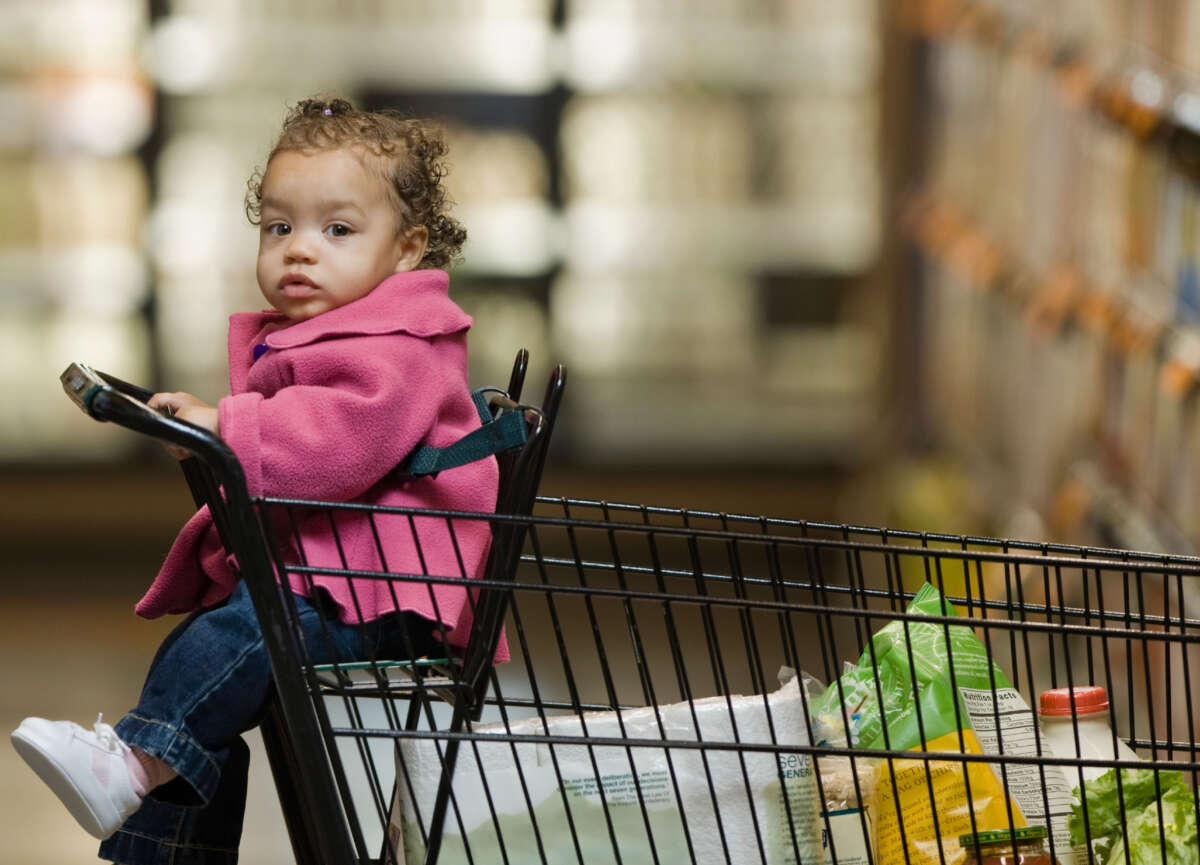 A baby sits in a grocery cart