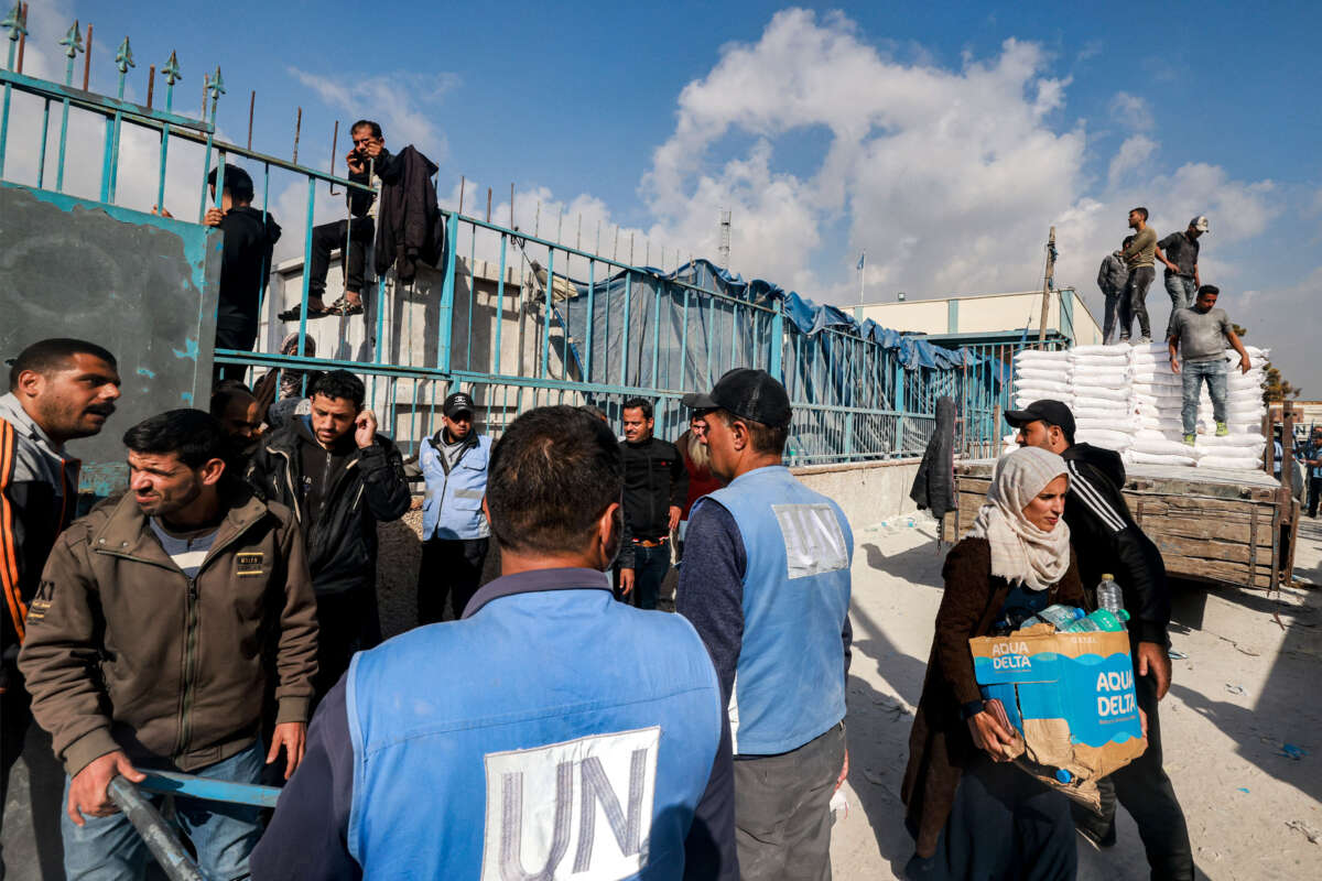 Workers of the United Nations Relief and Works Agency for Palestine Refugees (UNRWA) hand out flour rations and other supplies to people at an UNRWA warehouse in Rafah in the southern Gaza Strip on December 12, 2023.