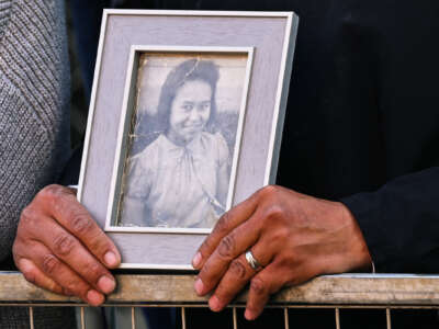 A person wearing a wedding band holds a black and white photo of their deceased family member who had been held captive at a Canadian boarding school