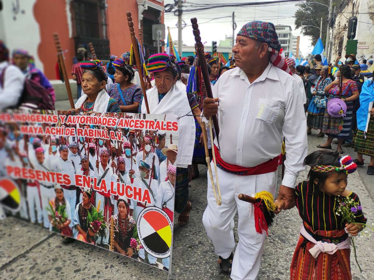 Holding his granddaughter’s hand, Miguel Ángel Alvarado and other Indigenous Maya Achi leaders march for democracy in Guatemala City.