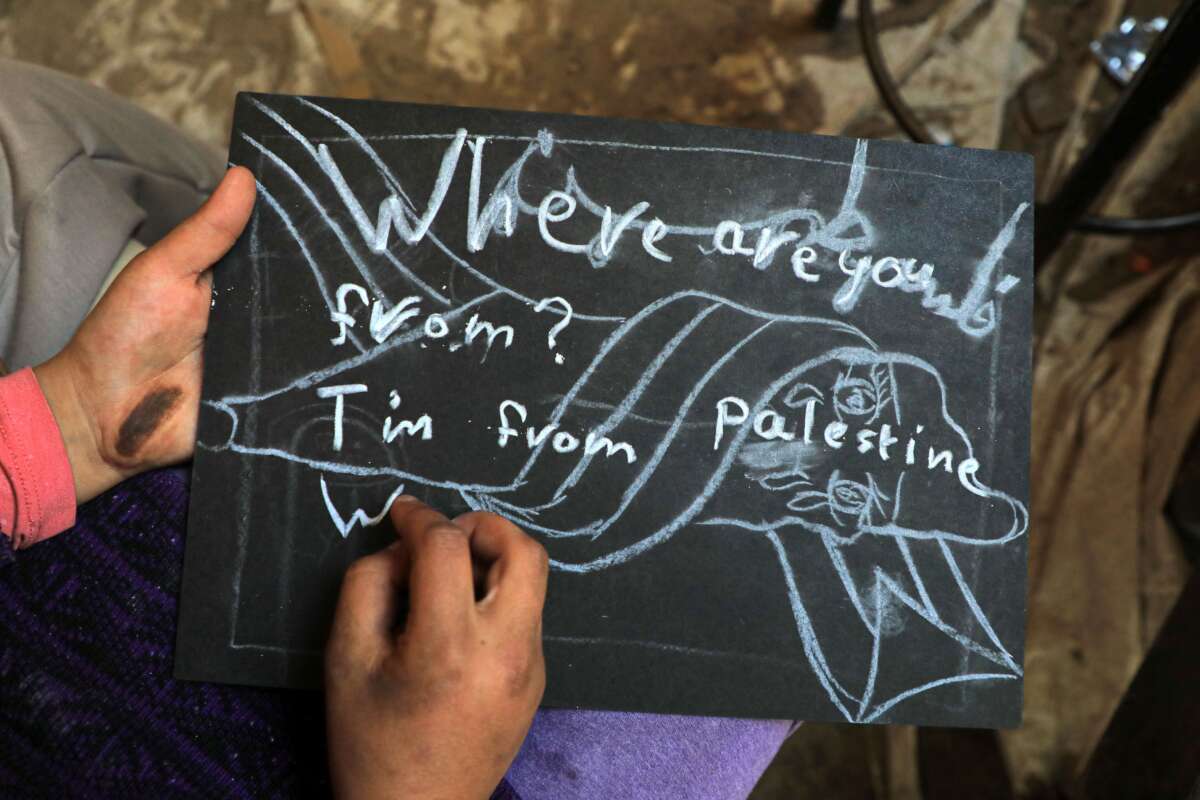 A student writes down "I am from Palestine" at a temporary classroom in the southern Gaza Strip city of Rafah, on December 28, 2023.