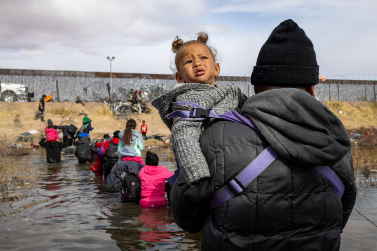 A migrant man crosses the Rio Grande holding his child in the air to prevent her from getting wet in Ciudad Juarez, Mexico, on January 2, 2024.