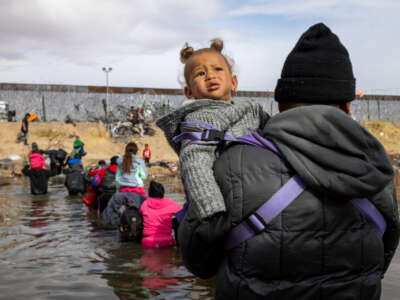 A migrant man crosses the Rio Grande holding his child in the air to prevent her from getting wet in Ciudad Juarez, Mexico, on January 2, 2024.