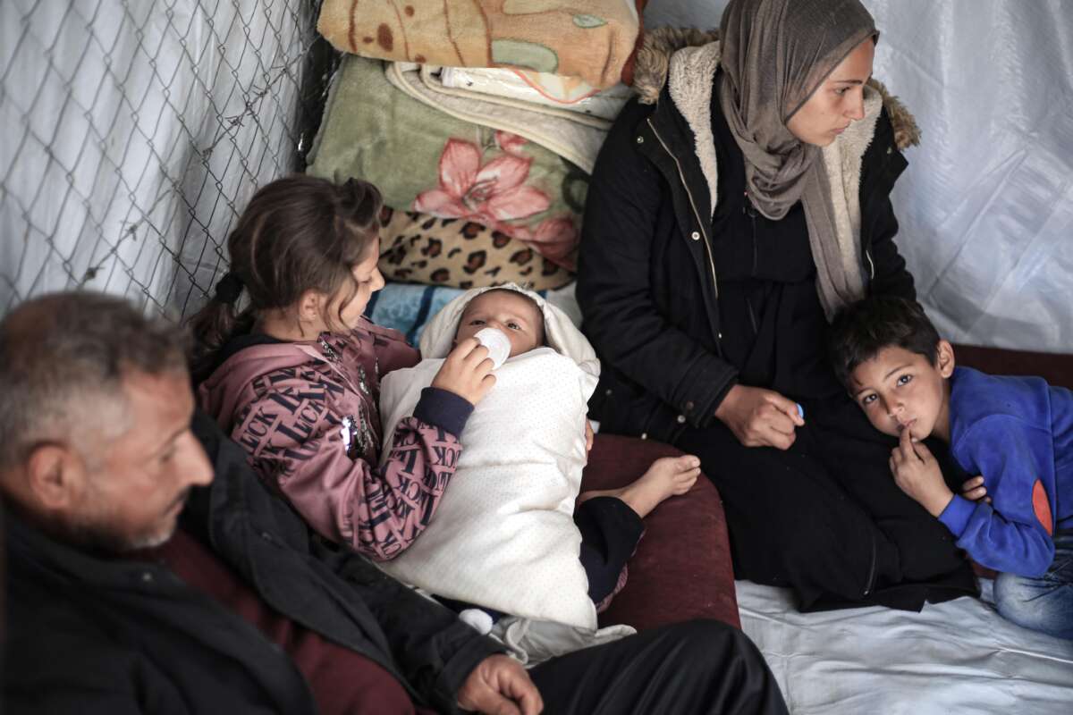 Family members of a child, born on October 7, interact with him inside a tent near the Gaza-Egypt border in Rafah, on January 14, 2024.