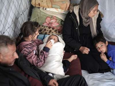 Family members of a child, born on October 7, interact with him inside a tent near the Gaza-Egypt border in Rafah, on January 14, 2024.