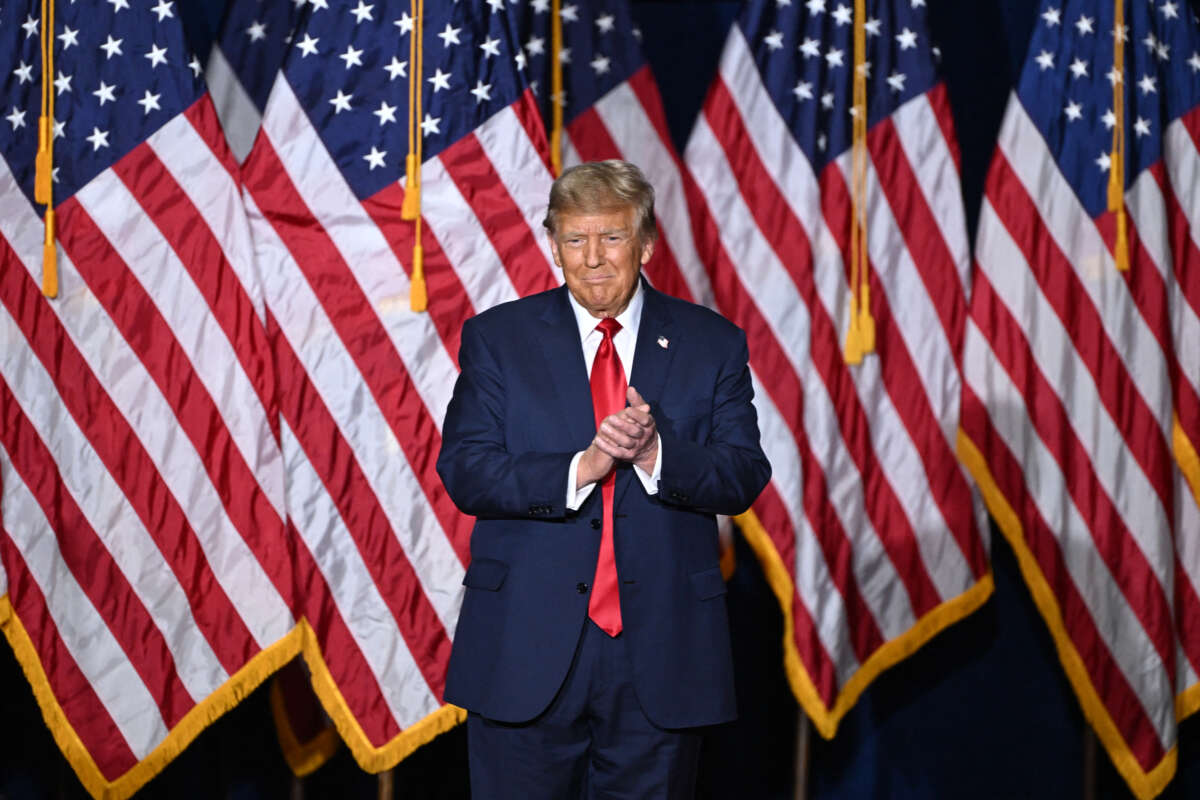 Donald Trump stands in front of a line of American flags