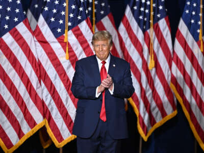 Donald Trump stands in front of a line of American flags