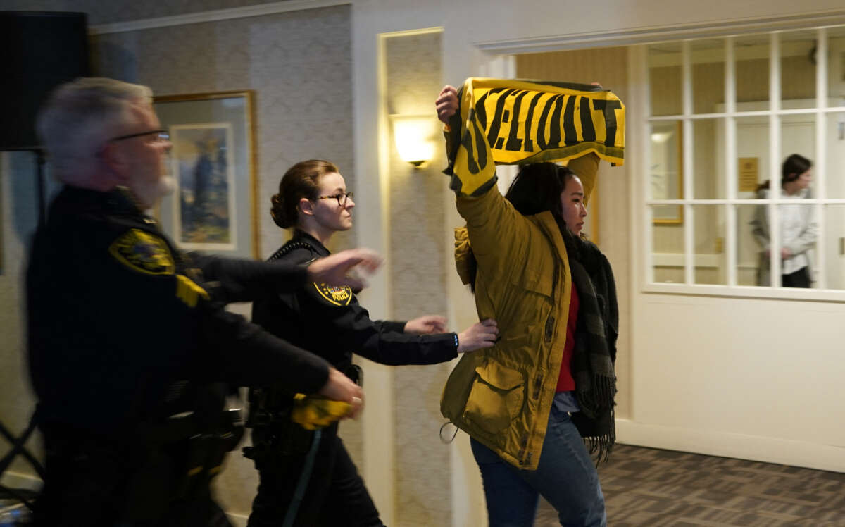 A Sunrise Movement youth climate protestor is led out by police after disrupting former President Donald Trump campaign rally in Laconia, New Hampshire, on January 22, 2024. Youth climate activists are targeting "climate criminal" politicians as part of a larger primary-focused strategy targeting both Republicans and Democrats as election season ramps up.