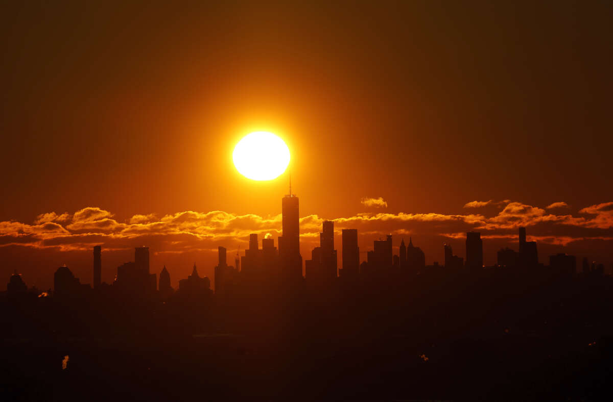 The sun rises behind the skyline of lower Manhattan and One World Trade Center in New York City, on January 21, 2024.