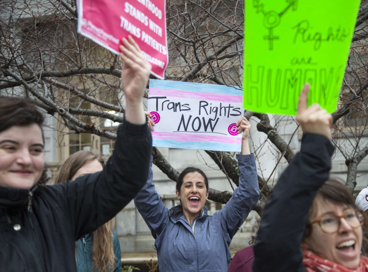 Protester holds sign saying "trans rights now!" at rally in maine