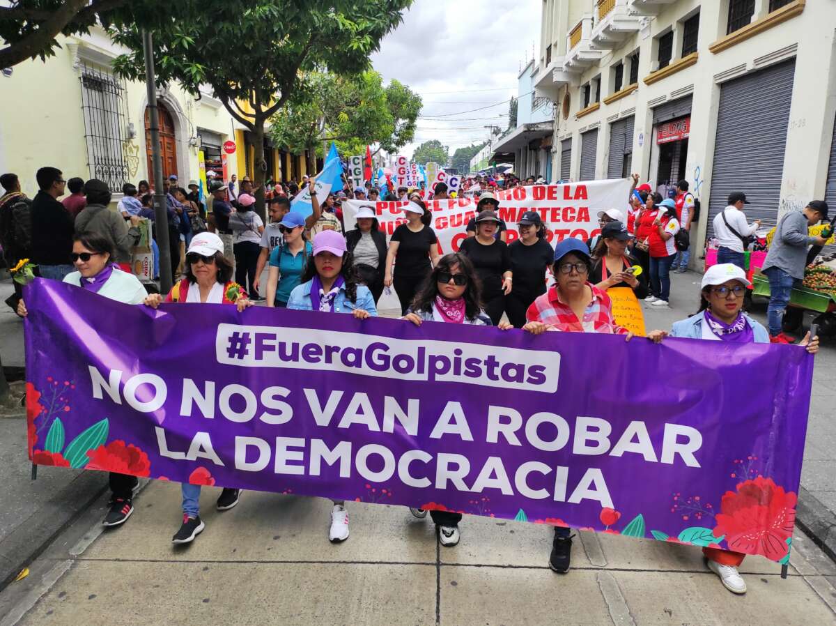 Women march holding a banner that reads “They Will Not Steal Democracy From Us” at a march in Guatemala City.