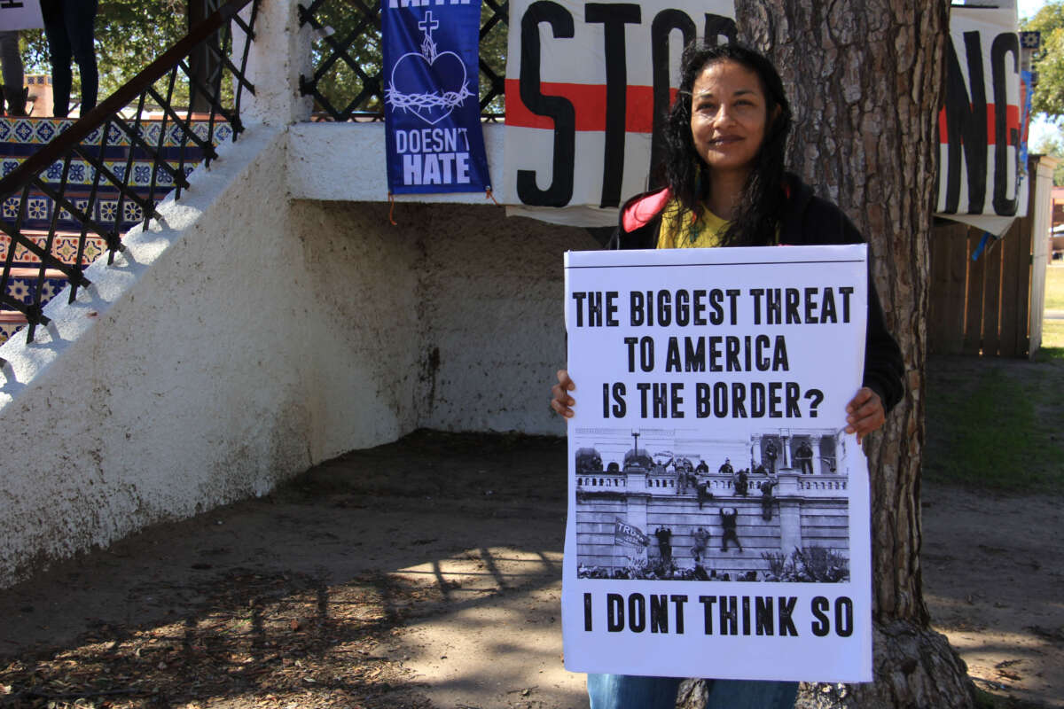 An organizer from the No Border Wall Laredo Coalition poses with a sign in San Juan Park on February 4, 2024, in Eagle Pass, Texas.