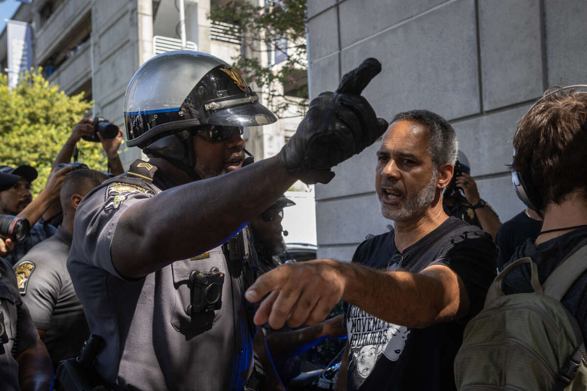 A police officer and a protester argue as protesters of "Cop City" approach the Lewis R. Slaton Courthouse ahead of an expected indictment of former President Donald Trump in Atlanta, Georgia, on August 14, 2023.