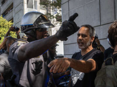 A police officer and a protester argue as protesters of "Cop City" approach the Lewis R. Slaton Courthouse ahead of an expected indictment of former President Donald Trump in Atlanta, Georgia, on August 14, 2023.