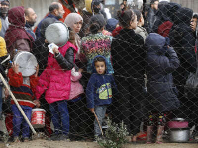 Palestinians wait in food queues that a cookhouse distributes with their containers for hours despite cold weather as Israeli attacks continue in Deir Al Balah of Gaza on February 2, 2024.