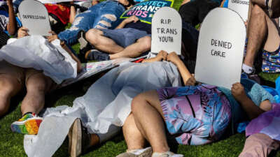 Protesters lie on the ground holding cardboard signs shaped like tombstones in front of the Marriott Fort Lauderdale Airport as the Florida Board of Medicine meets inside, on August 2, 2023.