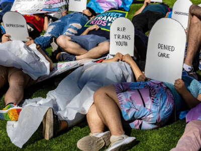 Protesters lie on the ground holding cardboard signs shaped like tombstones in front of the Marriott Fort Lauderdale Airport as the Florida Board of Medicine meets inside, on August 2, 2023.