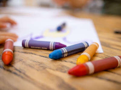 A close-up shot of colorful crayons on a wooden table with paper.