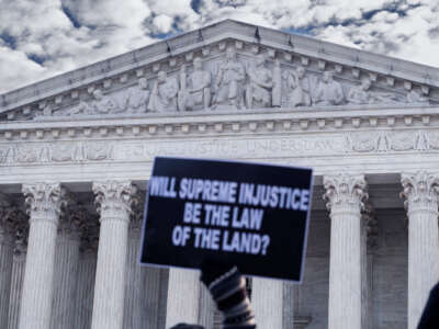 A person holds a sign reading "WILL SUPREME INJUSTICE BE THE LAW OF THE LAND?" during a protest on the steps of the US Supreme Court building