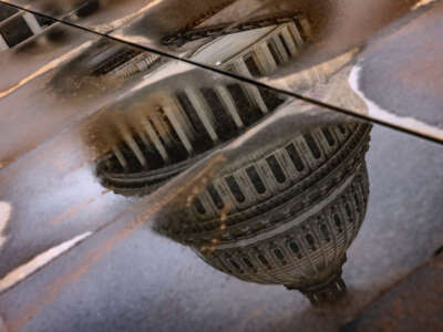 The U.S. Capitol building is seen reflected in rain puddles on February 11, 2024, in Washington, D.C.