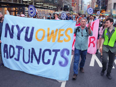 People march behind a banner reading "NYU OWES ADJUNCTS" during an outdoor protest