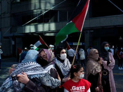 People hold the Palestinian flag and embrace during an outdoor protest