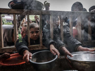 Displaced Palestinian children gather to receive food at a government school in Rafah in the southern Gaza Strip on February 19, 2024.